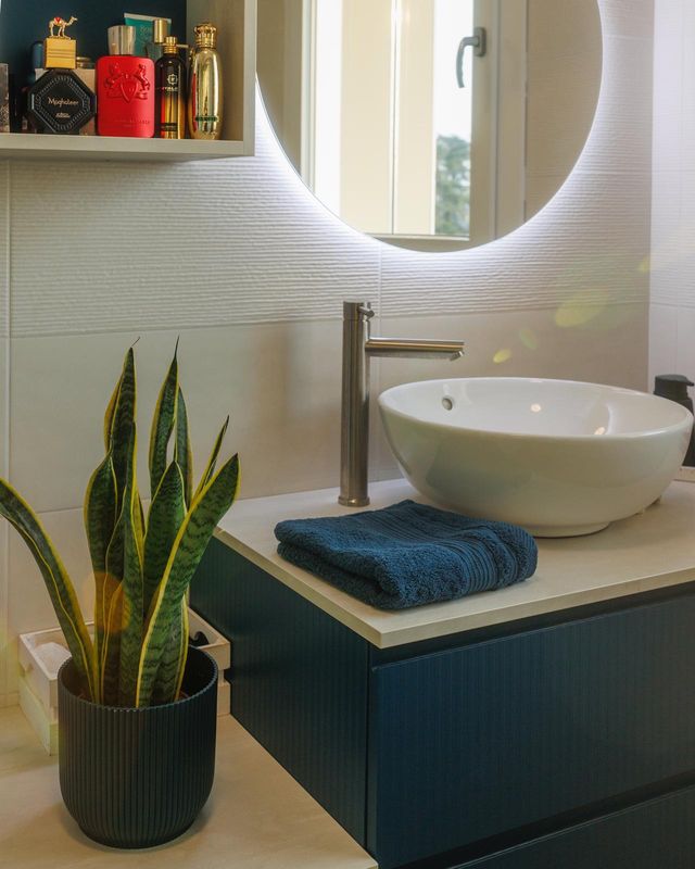 Il bagno con specchio tondo retroilluminato e mobile verde
